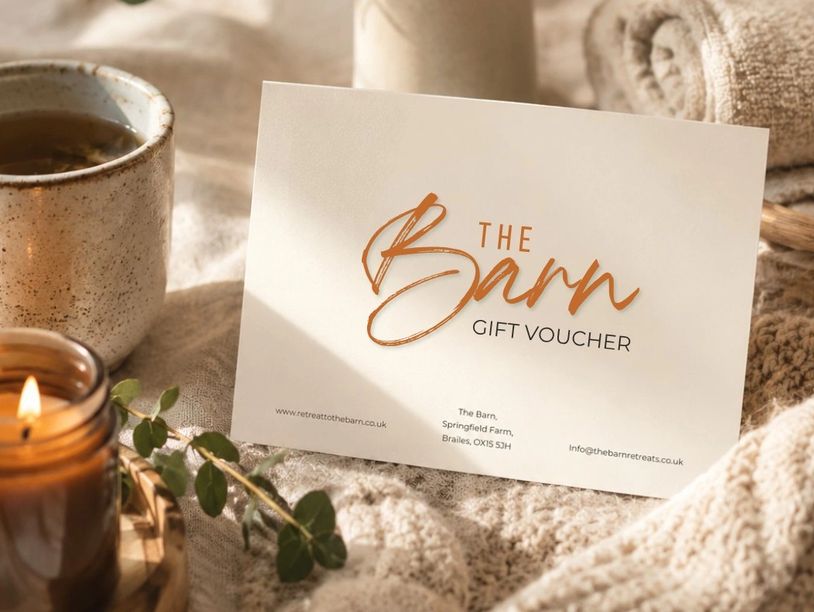 Cozy setting with The Barn gift voucher amid warm candles and soft blankets.