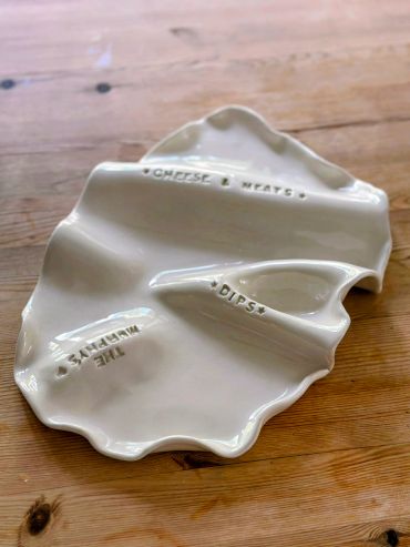 White ceramic serving dish with sections labeled for cheese, meats, dips, and white humus.