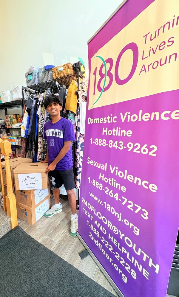 Young man standing by a domestic violence hotline sign with donation boxes.