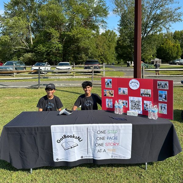 Two people at a GotBooksNJ table outdoors.