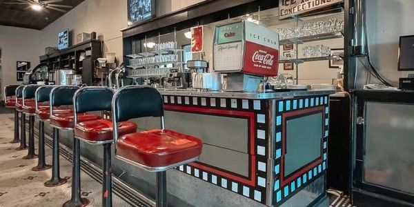Retro diner counter with red stools and vintage Coca-Cola sign.