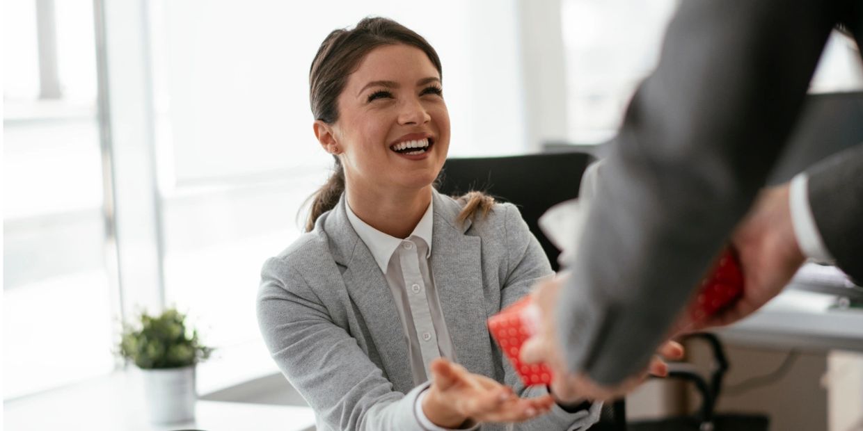 Givelist wish list page image with woman at office receiving a gift and smiling.