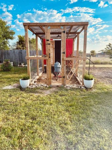 Wooden chicken coop with wire mesh under a blue sky.