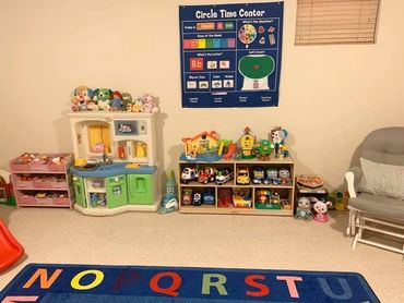 A colorful kids' playroom with toys, a play kitchen, and an educational wall chart.