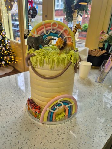 A safari-themed cake with animal figurines and colorful rainbows.