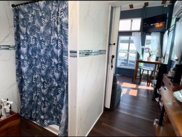 Cozy room with a bathroom featuring a patterned shower curtain and wooden furniture.