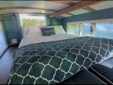 Cozy bed with scenic water views through large windows in a modern cabin.