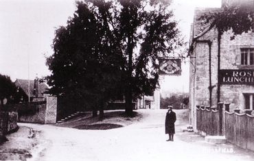 Historical image of a man in a cap standing outside the village pub in Nympsfield