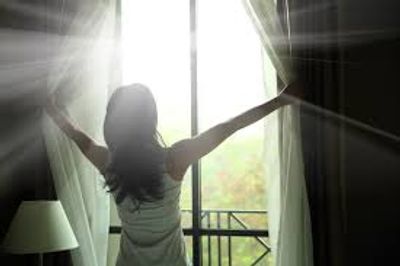 woman opening window with sunlight coming in