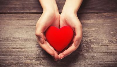 hand holding a felt heart on a wooden table