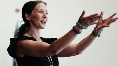 Woman speaking passionately with expressive hand gestures.