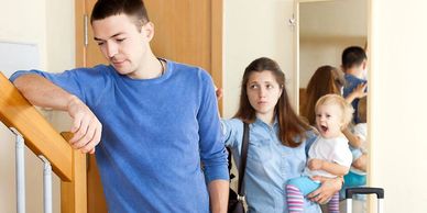 Mujer con hijo en brazos despidiéndose de su esposo