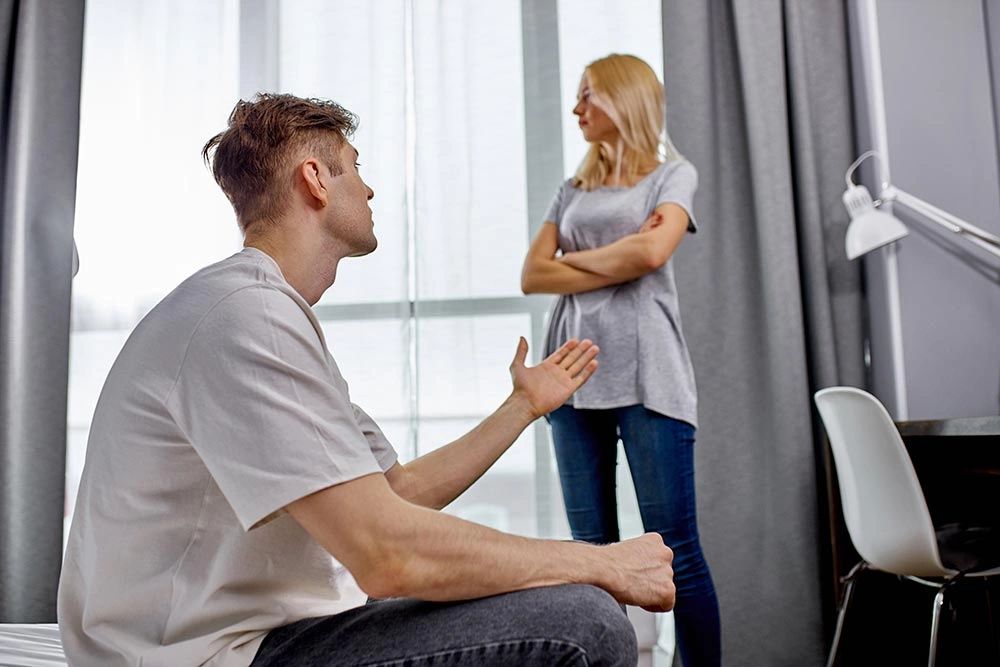 Hombre sentado en la cama explicando a la mujer