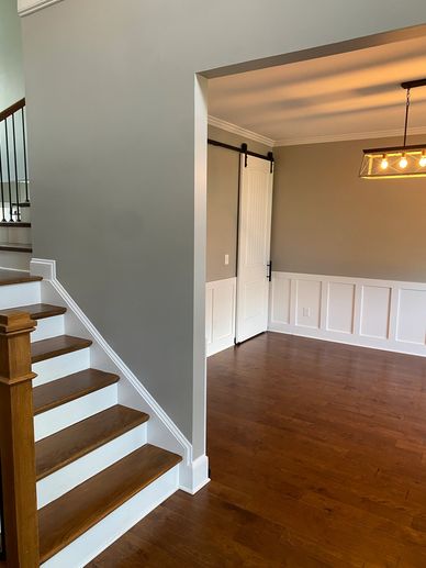 Empty modern room with wooden stairs and barn door.