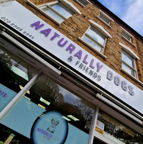 Shopfront of Naturally Dogs & Friends pet store with purple signage.