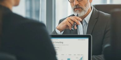 Two professionals engaged in a serious business discussion with a laptop showing data charts.