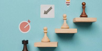 Chess pawns on ascending wooden blocks with icons symbolizing progress and ideas.