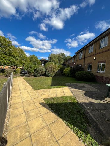 Building grounds with lawn area and paved walkway on a sunny day