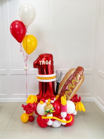 Colorful balloon arrangement with food-themed balloons and the number one.
