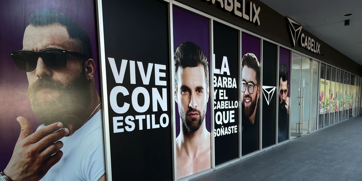 Storefront with stylish men's grooming advertisement featuring bearded models and bold text.