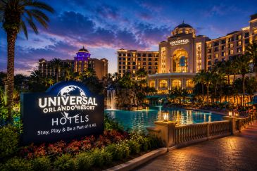 Universal Orlando Resort hotel illuminated at twilight with pool and palm trees.
