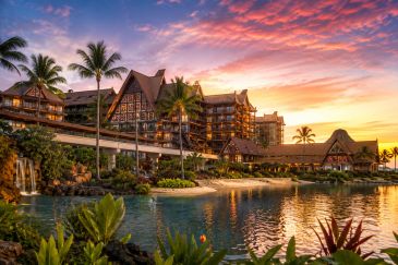 Tropical resort at sunset with palm trees and water reflections.