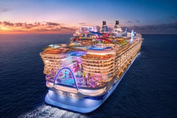 The illuminated Star of the Seas cruise ship at sunset in the open ocean.