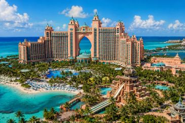A luxurious tropical resort with pools, water slides, and beachfront views under a bright blue sky.