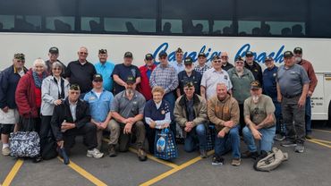 Group of veterans posing in front of a tour bus.