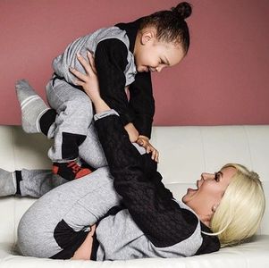 A joyful woman plays with a smiling child on a couch.