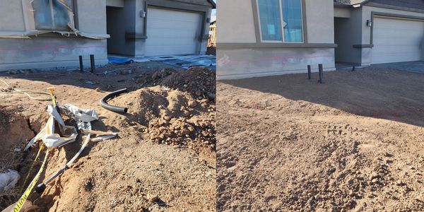 Orange excavator with a large bucket on a construction site under a cloudy sky
