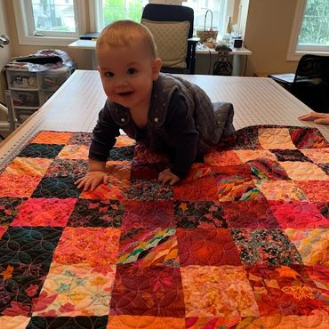 Grandson crawling on a picnic blanket quilt made by Sara