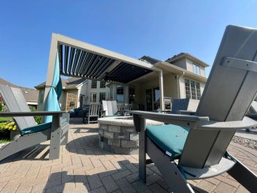 Cozy backyard patio with Adirondack chairs and a fire pit under a pergola.