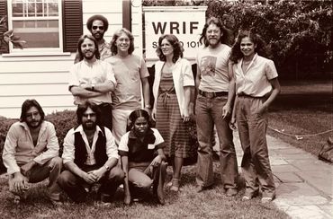Group photo of nine diverse adults outside a building with WRIF sign.