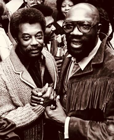 Two men warmly shaking hands at a social gathering.