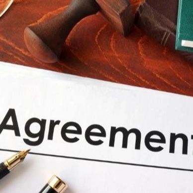 Close-up of an agreement document with a pen and stamp on a wooden table.