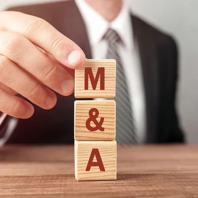 Businessman stacking blocks labeled M & A on a wooden table.
