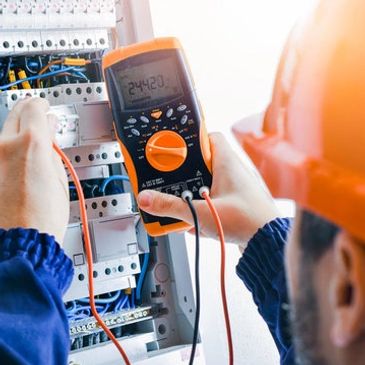 An electrician using a multimeter to check the voltage on the circuit breaker