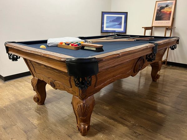 Classic wooden pool table with billiard balls and cues ready to play.