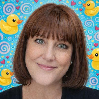 Smiling woman with red hair and a playful rubber duck background.