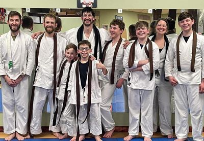 Group of karate students posing with brown belts.
