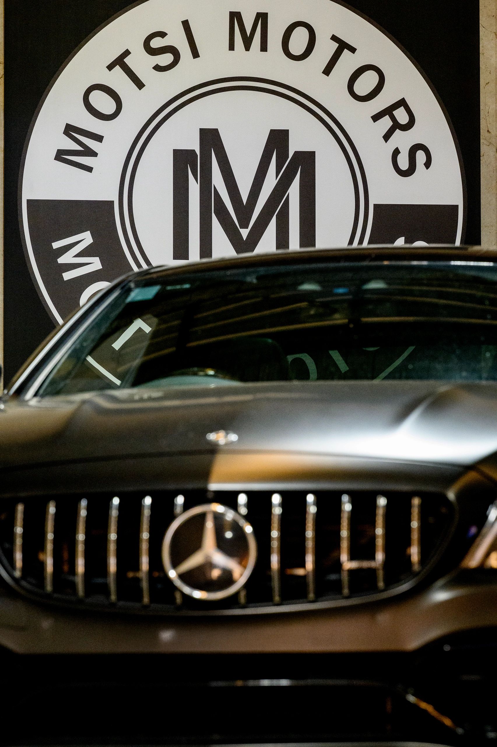 Front view of a Mercedes-Benz car in front of a Motsi Motors sign.