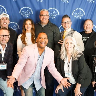 A group of smiling professionals posing at a real estate event.
