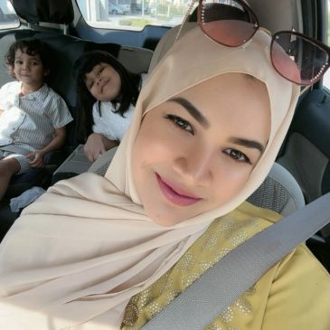 Woman in hijab with two children in car.