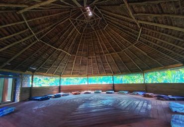 Sala circular con techo de madera y cojines.