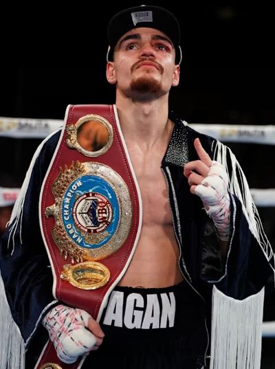 Boxer with championship belt and wrapped hands in the ring.