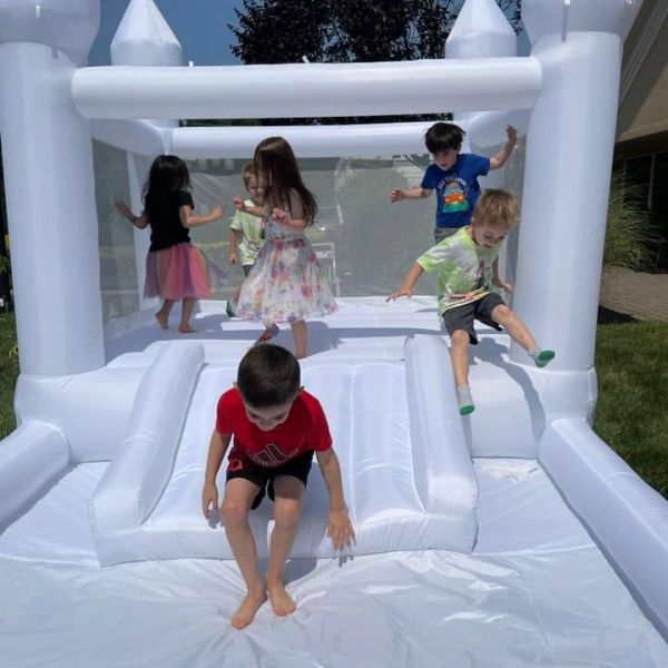 Children playing on a white inflatable bounce house.