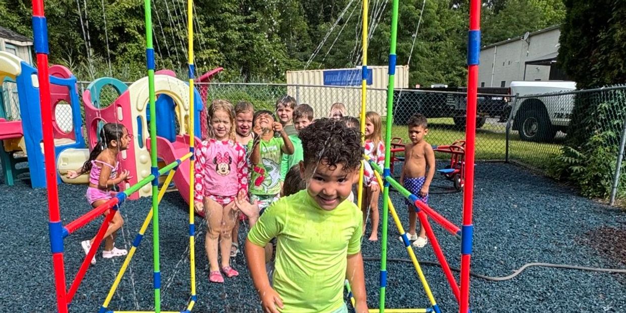 Kids playing on playground equipment with water sprayers.
