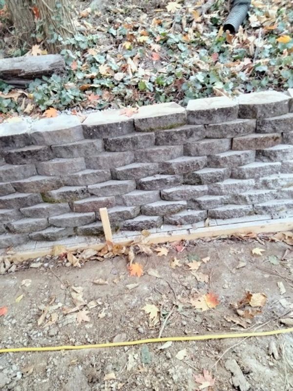 Stone retaining wall with ground and leaves.
