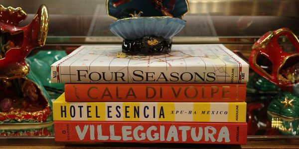 Stack of colorful books on a shelf with decorative objects around.